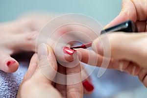 Closeup of manicurist applying nail polish