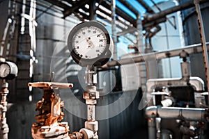 Closeup of manometer, measuring gas pressure. Pipes and valves at industrial plant