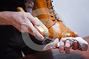 Closeup of Mans Hands with Cleaning Brush Used for Polishing Tan High Derby Boots