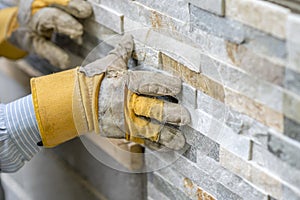 Closeup of manual worker in protection gloves pushing the tile i