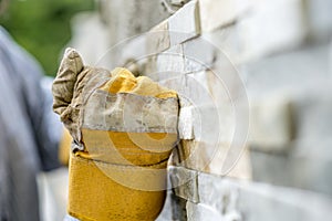 Closeup of manual worker in protection gloves tiling a wall wit