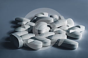 Closeup of many white prescription drugs, medicine tablets or vitamin pills in a pile - Concept of healthcare, opioids addiction