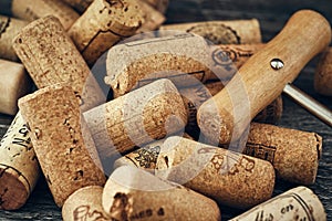 A closeup of many wine corks and a classic corkscrew