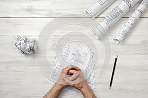 Closeup masculine folded hands on wooden panel with hand-folding a piece of paper.