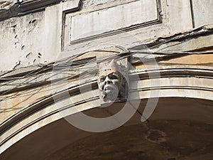 Closeup of masks of stone on arches worn by time