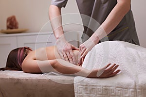 Closeup masseur hands pouring massaging oil to female back preparing to relaxing or revitalizing massage.