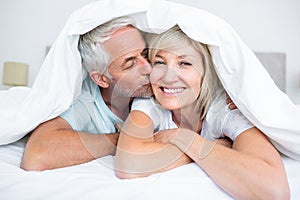 Closeup of mature man kissing womans cheek in bed