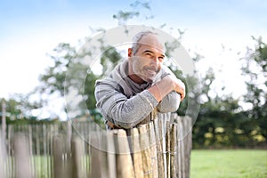 Closeup of mature man leaning on wood fence