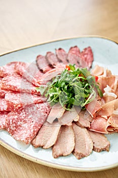 Closeup Meat plate, delicacy and Anantipasto. Salami, roast beef, Parma ham, smoked duck breast. Restaurant menu.