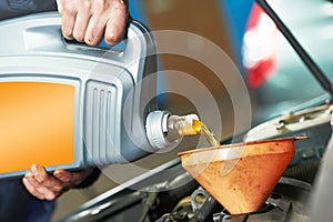 Closeup mechanic hand pouring oil into car motor