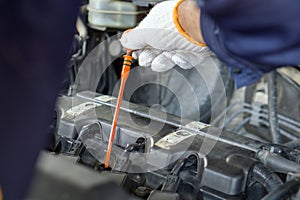 Closeup mechanic hand with protective glove checking the oil level of a car. Routine car maintenance for safe and efficient engine