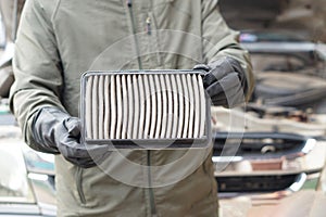 Closeup mechanic's hands hold air filter pad of car engine to check.