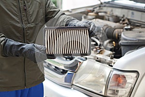 Closeup mechanic's hands hold air filter pad of car engine to check.
