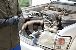 Closeup mechanic's hands hold air filter pad of car engine to check.