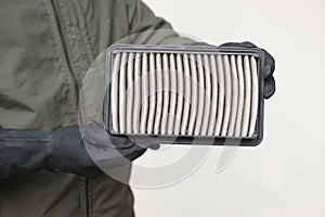 Closeup mechanic's hands hold air filter pad of car engine to check.