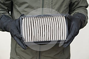 Closeup mechanic's hands hold air filter pad of car engine to check.