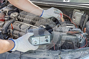 A closeup of a mechanics hands using jumper cables on a car battery. checking of car battery