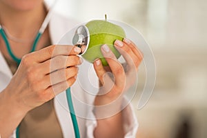 Closeup on medical doctor woman examining apple