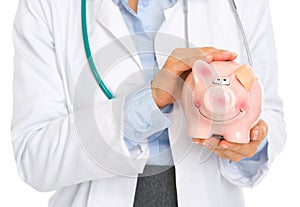 Closeup on medical doctor woman holding piggy bank