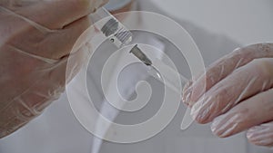 Closeup medical hands in gloves sucking liquid medicine from ampoule with syringe needle. Medical worker preparing