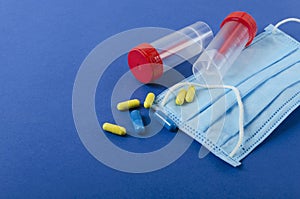 Closeup of medical mask, plastic containers , pills on the blue background