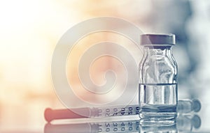 Closeup of medicine vial or flu, measles vaccine bottle with syringe and needle for immunization on vintage medical background,