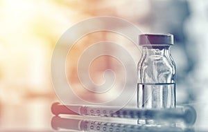 Closeup of medicine vial or flu, measles vaccine bottle with syringe and needle for immunization on vintage medical background,