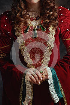 Closeup on medieval queen in red dress on dark gray background