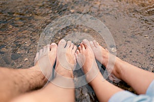 Closeup Men`s feet and women`s feet soaked in stream water