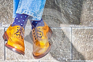 Closeup of Mens Legs Wearing Brown Oxfords Semi Brogues Shoes. Posing Outdoors Against Stony Grunge Background