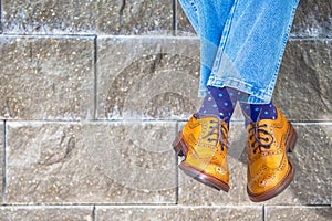 Closeup of Mens Legs Wearing Brown Oxfords Semi Brogues Shoes. Posing Outdoors Against Stony Grunge Background photo