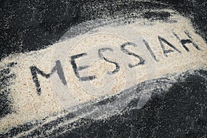 Closeup of MESSIAH text written on white sand photo