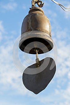 Closeup of metal buddhist bell with heart shape on sky background.