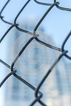 Closeup of a metal mesh fence, with blurred out bokeh background