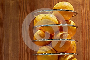 Closeup metal spiral holder with oranges against photo