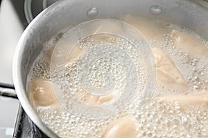 Closeup of metal stewpan with boiling water and dumplings.