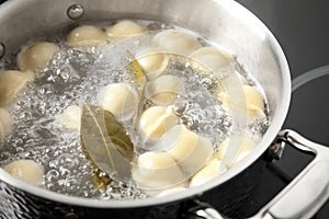 Closeup of metal stewpan with boiling water and dumplings