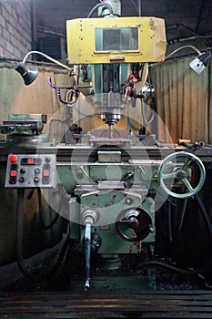 Closeup of metallic lathe drilling against factory industrial interior background