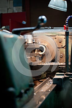 Closeup of metallic lathe working against factory industrial interior background