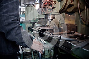 Closeup of metallic lathe working against factory industrial interior background