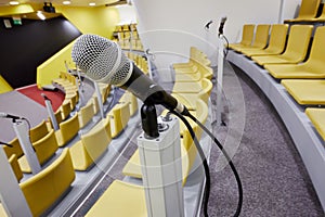 Closeup microphone in auditorium with chairs and photo