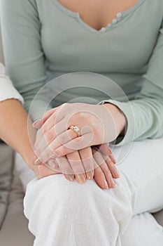 Closeup mid section of female friends touching hands