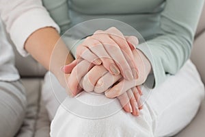 Closeup mid section of female friends touching hands