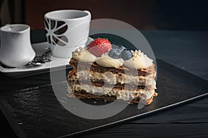 Closeup of a Mille-feuille cake with berries and a cup of coffee