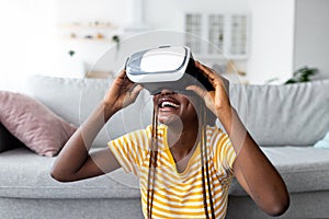 Closeup of millennial black woman using VR glasses at home