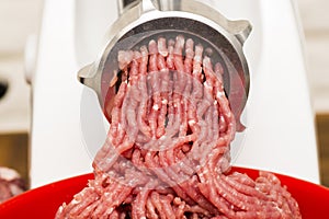 Closeup of minced meat coming out from grinder.