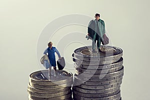 Miniature woman and man on piles of euro coins photo
