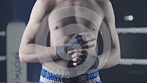 Closeup of a mixed martial arts fighter wrapping his hands before a fight. Boxer wraps his hand a red bandage before the