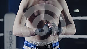 Closeup of a mixed martial arts fighter wrapping his hands before a fight. Boxer wraps his hand a red bandage before the