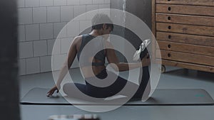 Closeup of mixed race african american woman makes a stretching routin on the floor in sunny loft